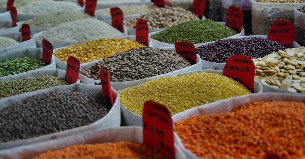 Bags of vibrant grains and spices on display in a bustling market setting.